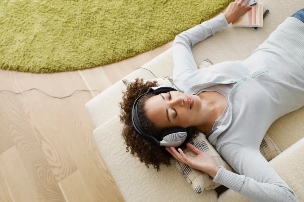 bien-être et relaxation : Votre Parenthèse avec maroussia bien-être Femme pratiquant la méditation allongée sur le sol avec un casque audio, relaxation et bien-être